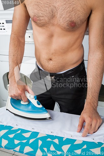 Image of Shirtless Man Ironing Shirt On Table