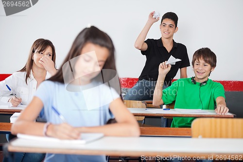 Image of Schoolboys Throwing Paperplane And Paperball On Girl