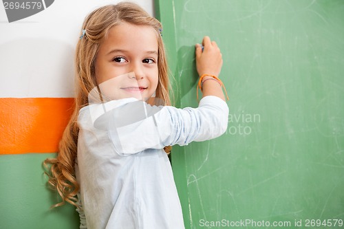 Image of Girl Looking Away While Writing On Chalkboard In Classroom