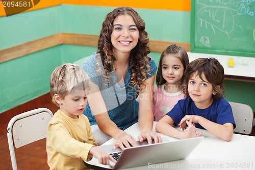 Image of Beautiful Teacher And Students With Laptop In Classroom