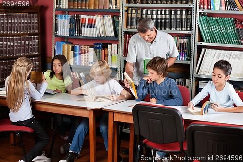 Image of Teacher Showing Book To Schoolboy In Library