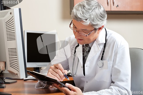 Image of Doctor Reading While Sitting At Desk