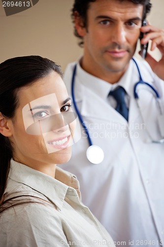 Image of Woman Smiling While Doctor Standing In Background
