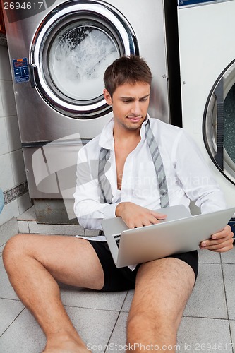 Image of Businessman Using Laptop In Laundromat