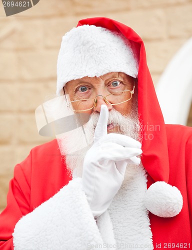 Image of Man Dressed As Santa Claus With Finger On Lips