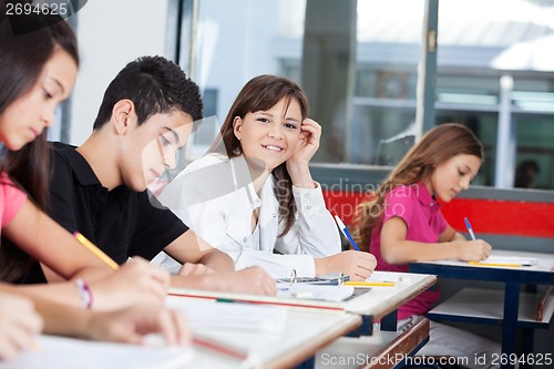 Image of Teenage Girl With Friends Writing At Desk