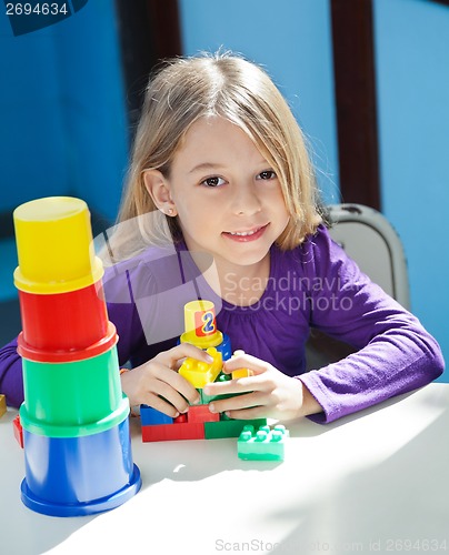 Image of Girl Sitting With Toys At Desk In Preschool