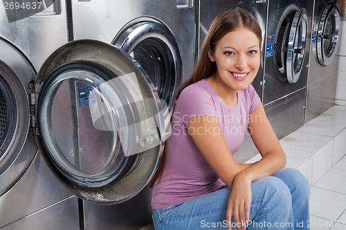 Image of Woman Sitting Against Washing Machines