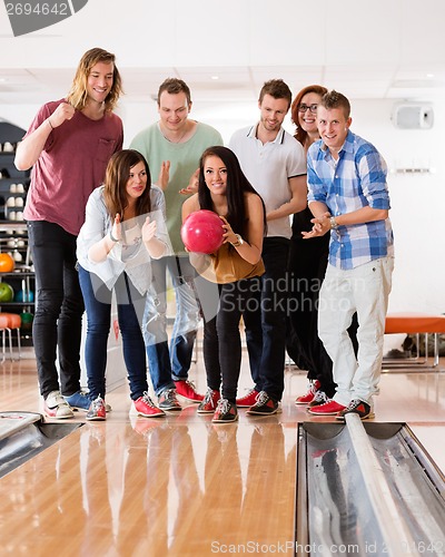 Image of Woman Bowling While Friends Cheering