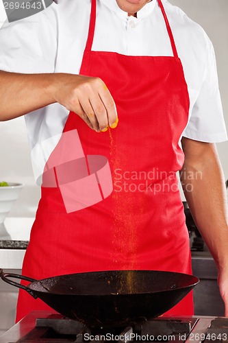 Image of Chef Adding Turmeric Powder In Pan