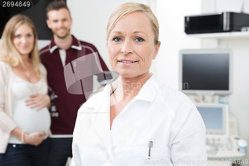 Image of Obstetrician With Expectant Couple In Background