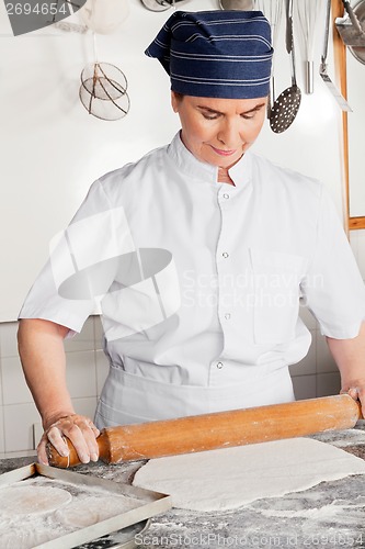 Image of Female Chef Rolling Dough On Counter