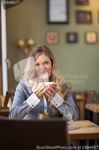 Image of Young Woman With Coffee Cup At Table