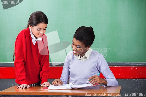 Image of Teacher And Schoolgirl Reading Together At Desk