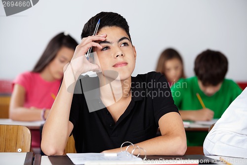 Image of Thoughtful Teenage Schoolboy Sitting At Desk