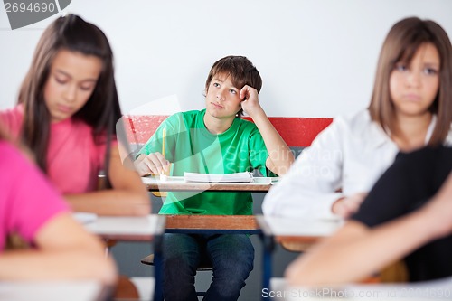 Image of Thoughtful Teenage Male Student Sitting At Desk