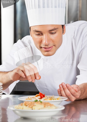 Image of Chef Sprinkling Spices On Dish