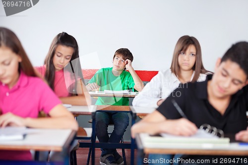 Image of Thoughtful Schoolboy Studying In Classroom