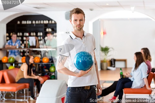 Image of Confident Young Man With Bowling Ball in Club