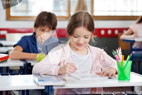 Image of Schoolgirl Smiling While Drawing In Classroom