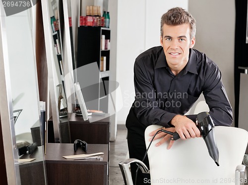 Image of Male Hairstylist With Hairdryer Leaning On Chair