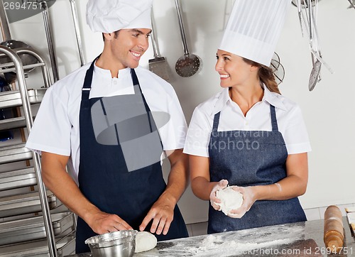 Image of Happy Chefs Kneading Dough In Kitchen