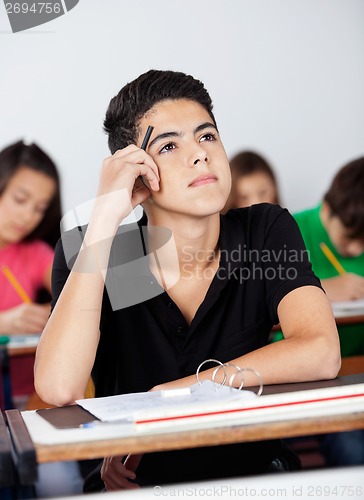 Image of Thoughtful Teenage Schoolboy Leaning At Desk