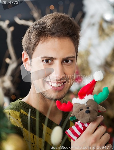Image of Man Holding Stuffed Toy In Christmas Store