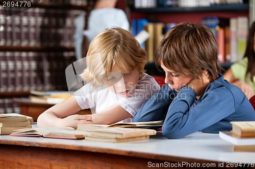 Image of Little Boys Reading Book Together In Library
