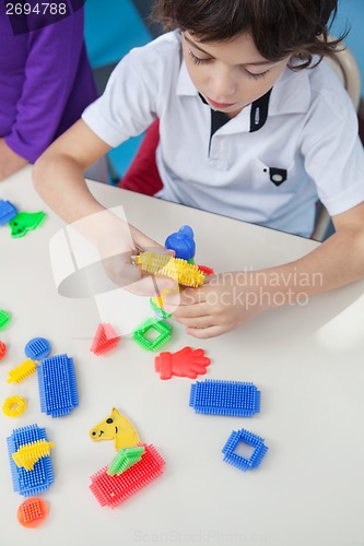 Image of Boy Playing With Blocks At Desk In Kindergarten