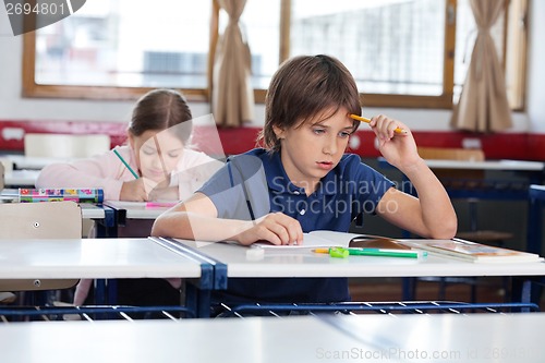 Image of Thoughtful Boy Sitting At Desk