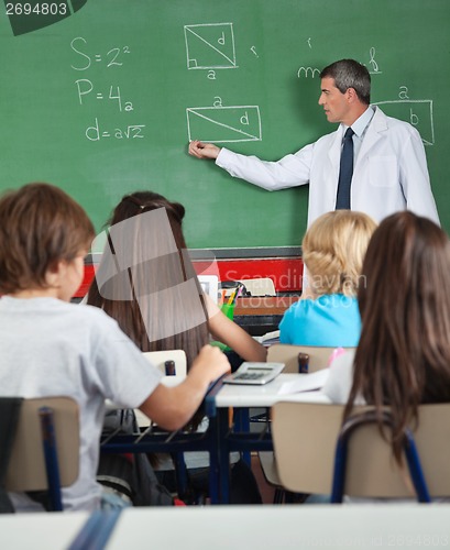 Image of Students Sitting At Desk While Teacher Teaching In Classroom