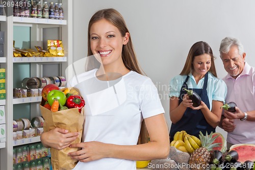 Image of Woman Holding Grocery Bag While People Shopping In Background