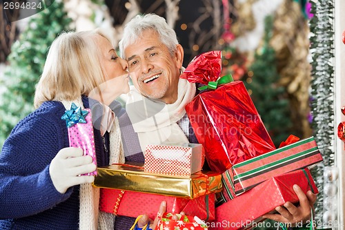 Image of Woman Kissing Man Holding Christmas Presents