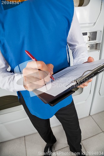 Image of Young Male Helper Checking List In Laundry