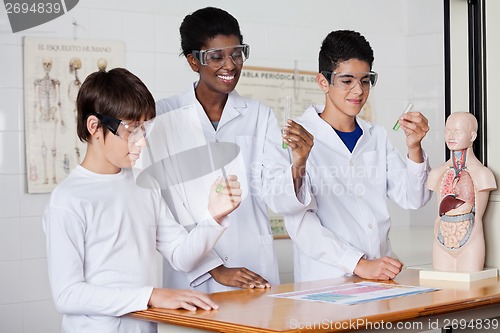 Image of Teacher With Students Examining Chemical Solution