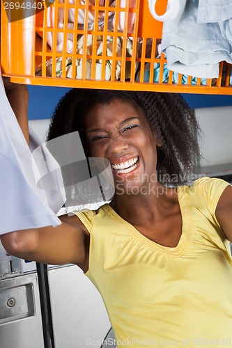 Image of Woman Carrying Basket Of Clothes In Laundromat