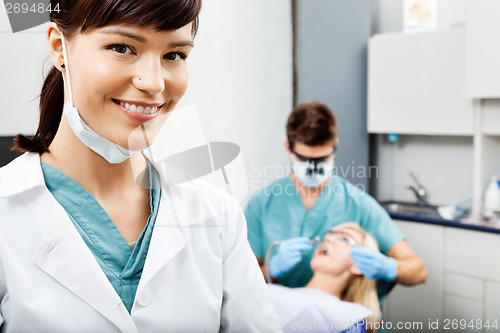 Image of Female Hygienist With Dentist Working In The Background