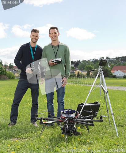 Image of Engineers Standing By UAV Helicopter And Tripod