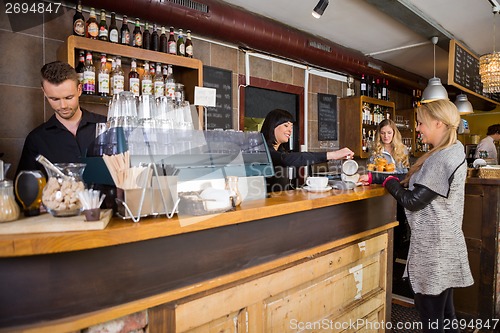 Image of Female Bartender Serving Coffee To Customer At Counter