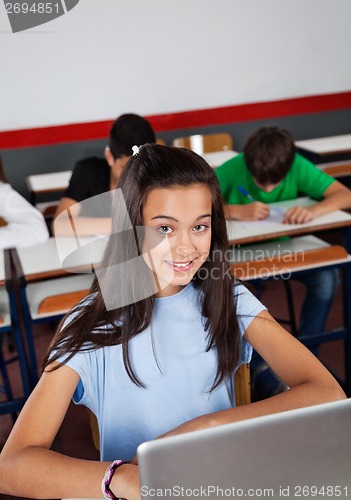 Image of Happy Teenage Schoolgirl Sitting With Laptop At Desk