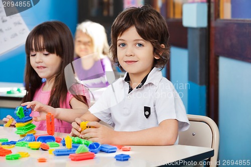 Image of Boy With Blocks While Friends Playing In Background