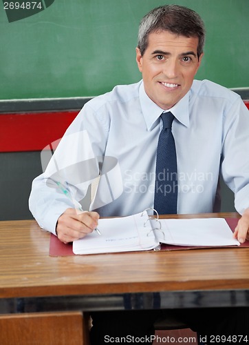 Image of Male Teacher Sitting With Pen And Binder At Desk