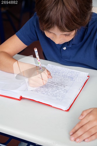 Image of Little Schoolboy Reading Book At Desk