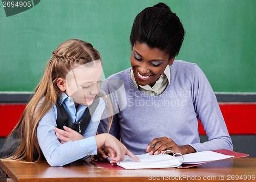 Image of Teacher Assisting Schoolgirl At Desk