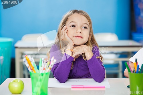 Image of Thoughtful Girl With Hand On Chin Sitting At Desk