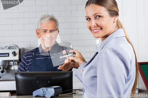 Image of Woman Giving Credit Card To Cashier At Counter