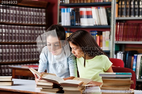 Image of Little Girls Reading Book Together In Library