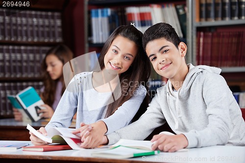 Image of Teenage Couple Holding Hands While Sitting In Library