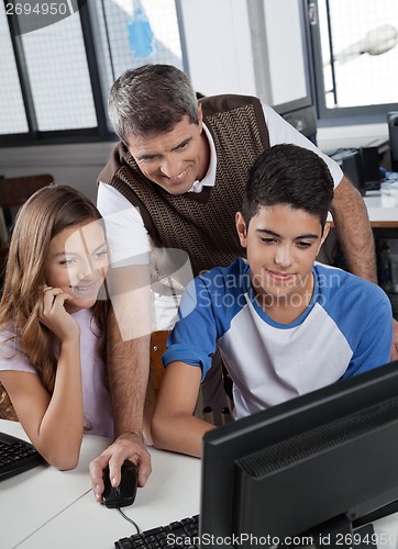 Image of Male Teacher With Schoolchildren Using Computer At Desk